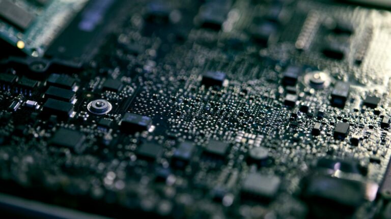 Close Up Of Electronic Circuit Board Of Laptop Being Repaired In Workshop With Low Key Lighting